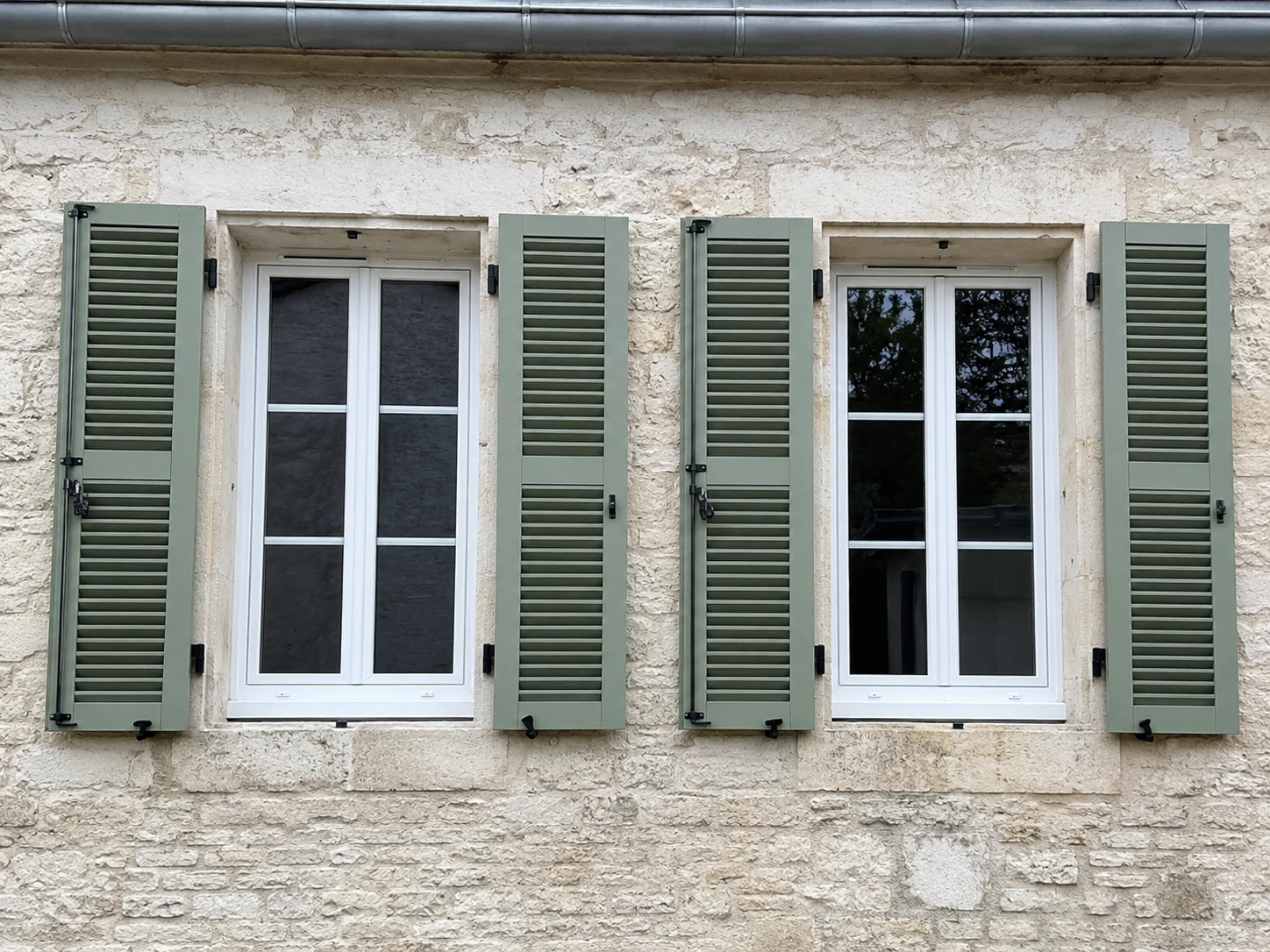 Volets battants en aluminium sur la façade en pierre d'une maison charentaise